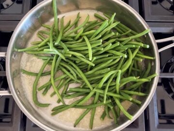 Adding the haricot verts to the melted butter in the skillet.