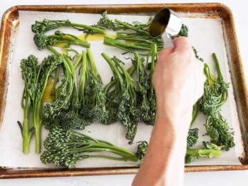 Adding oil to the broccolini.