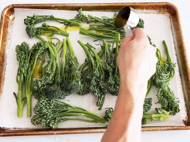 Adding oil to the broccolini.