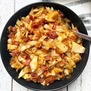 Fried cabbage is served in a bowl with a spoon and a napkin.