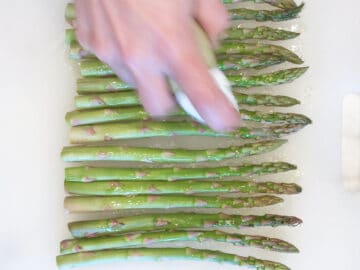 Spraying the asparagus with oil.
