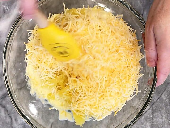 Adding shredded cheese to the bowl.