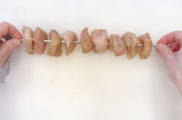 Threading the chicken pieces on skewers.
