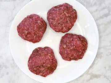 Four shaped beef sausages on a plate.
