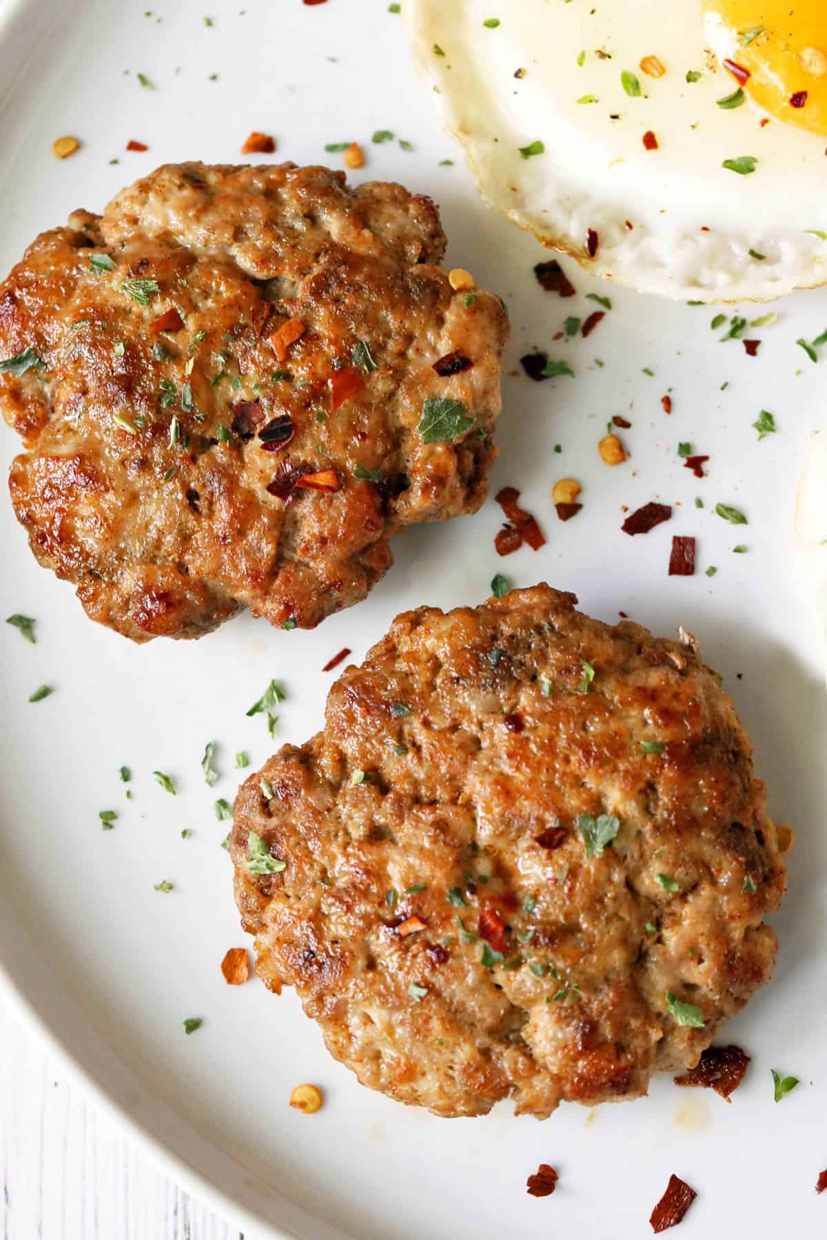 Sausage patties are served with fried eggs.