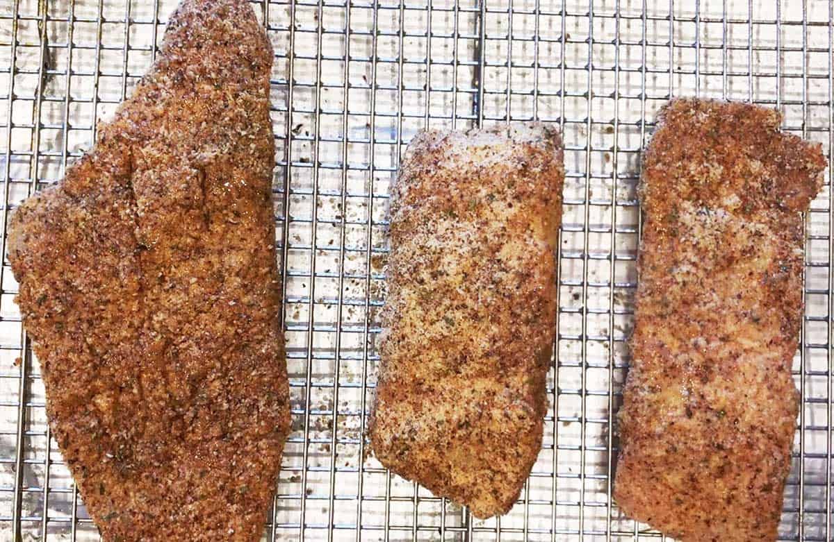 Three pieces of catfish on a baking sheet.