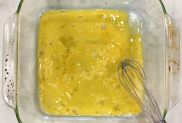 Whisking an egg and milk in a shallow container.