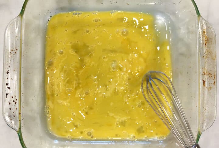 Whisking an egg and milk in a shallow container.