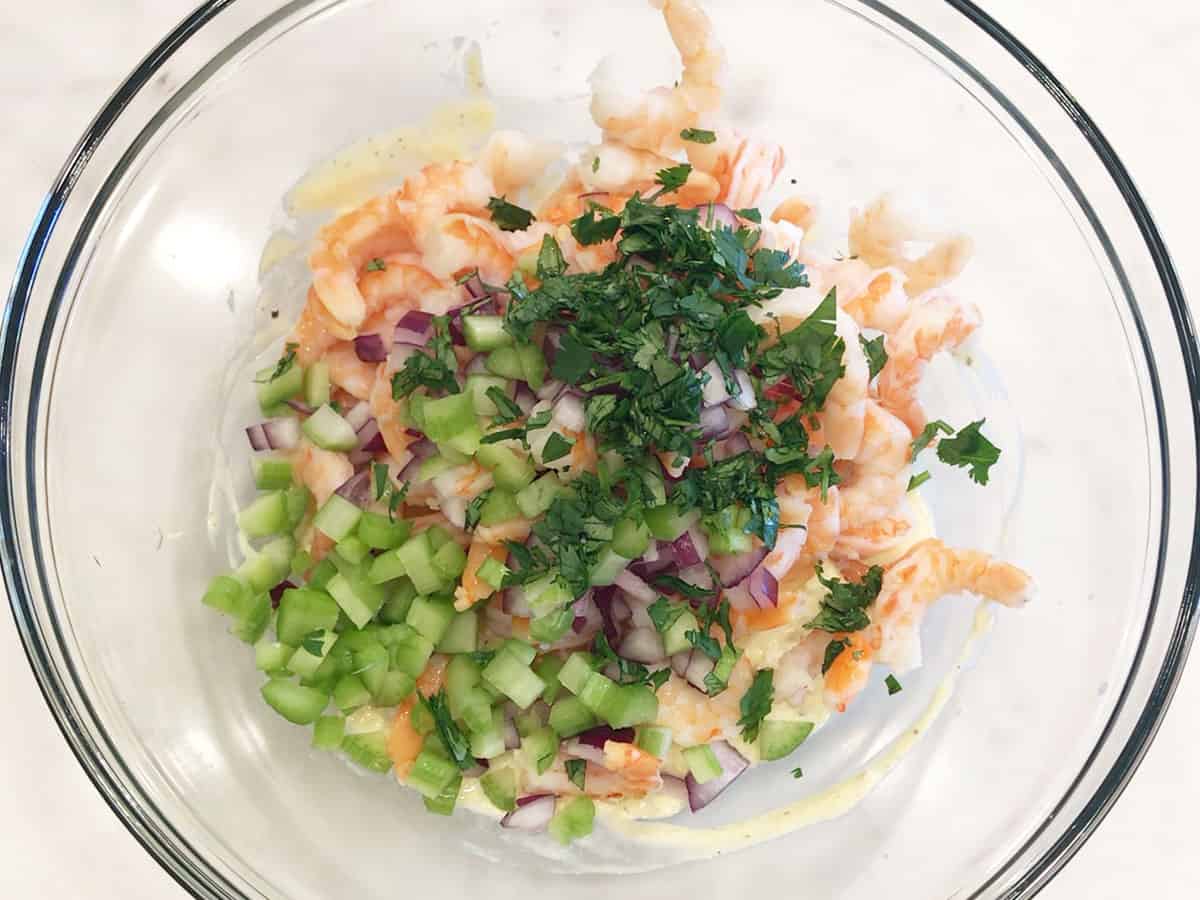 Adding the salad ingredients to the dressing.