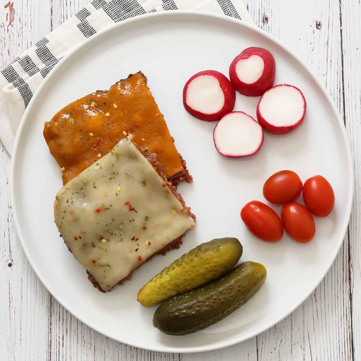 Leftover baked hamburgers are served with veggies and pickles.