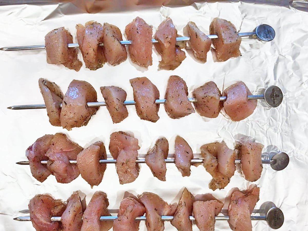 Raw chicken kabobs on a pan, ready to be baked.