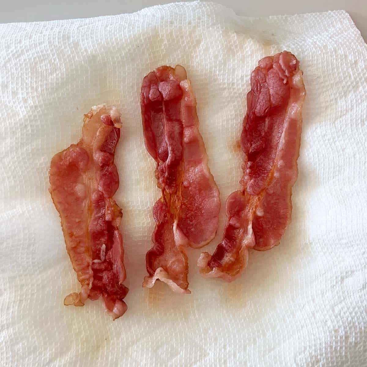Three slices of bacon that were microwaved for two minutes and came out soft.