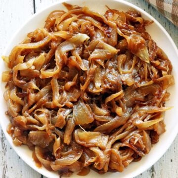 Caramelized onions are served on a white plate with a napkin.