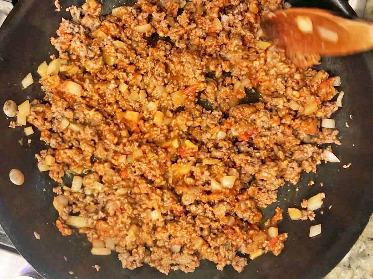 Cooking ground beef and onions in a skillet.