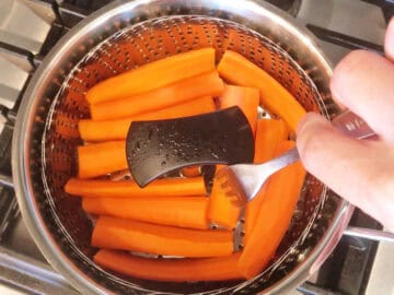 Checking that the carrots are fork-tender.