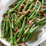 Green beans with bacon are served with a serving spoon.