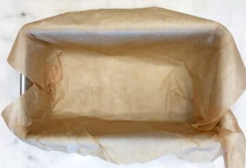 A loaf pan is lined with parchment paper.