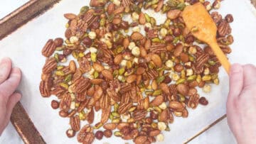Spreading the coated nuts on the baking sheet.