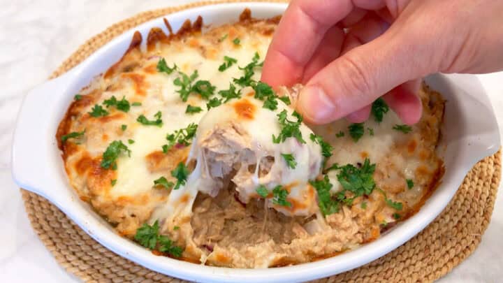 Scooping the hot casserole with a pork rind.