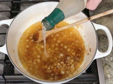 Adding clam juice to the pot.