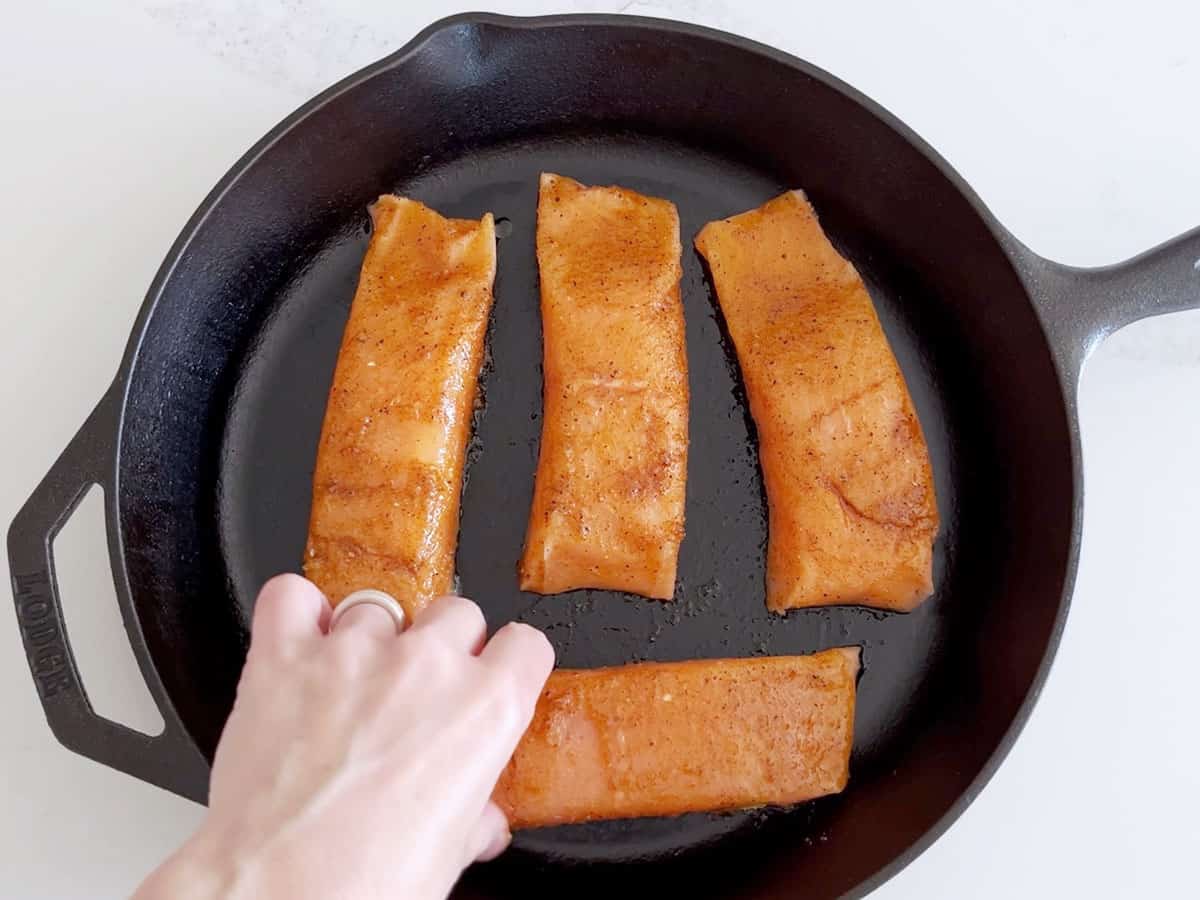 Arranging the seasoned salmon fillets in the pan.