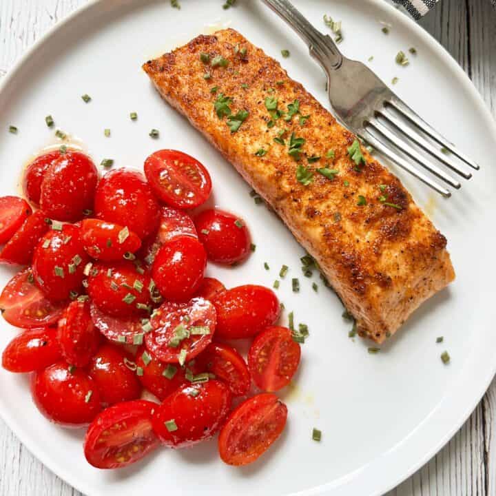 Broiled salmon is served with tomato salad.