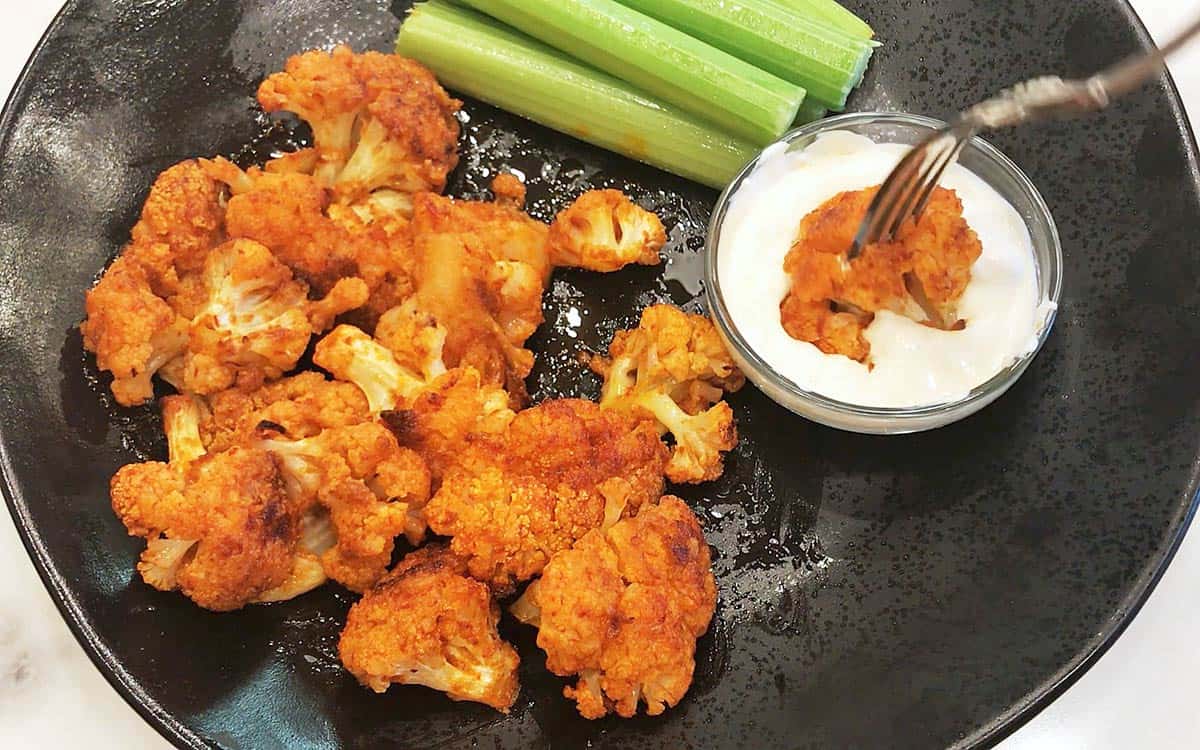 Dipping buffalo cauliflower into blue cheese dressing.