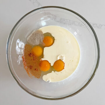Eggs, heavy cream, white pepper, and cayenne pepper in a bowl.