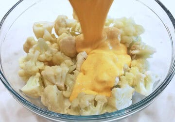 Pouring the cheese sauce on the cauliflower.