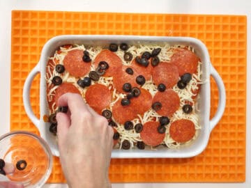 Topping the chicken with olives.