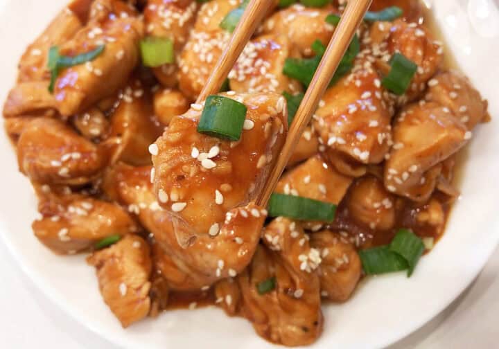 Keto sesame chicken is served with chopsticks.