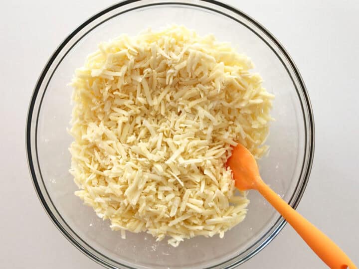 Shredded cheese were mixed with cornstarch and spices in a bowl.