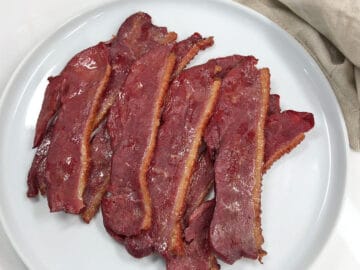 The bacon is served on a white plate.