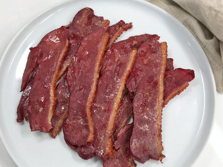 The bacon is served on a white plate.