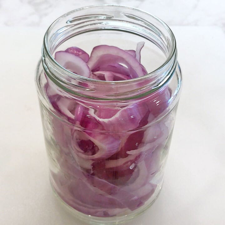 Red onion slices in a jar.