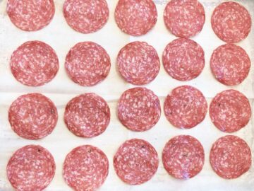 The salami was arranged on a parchment-lined baking sheet.