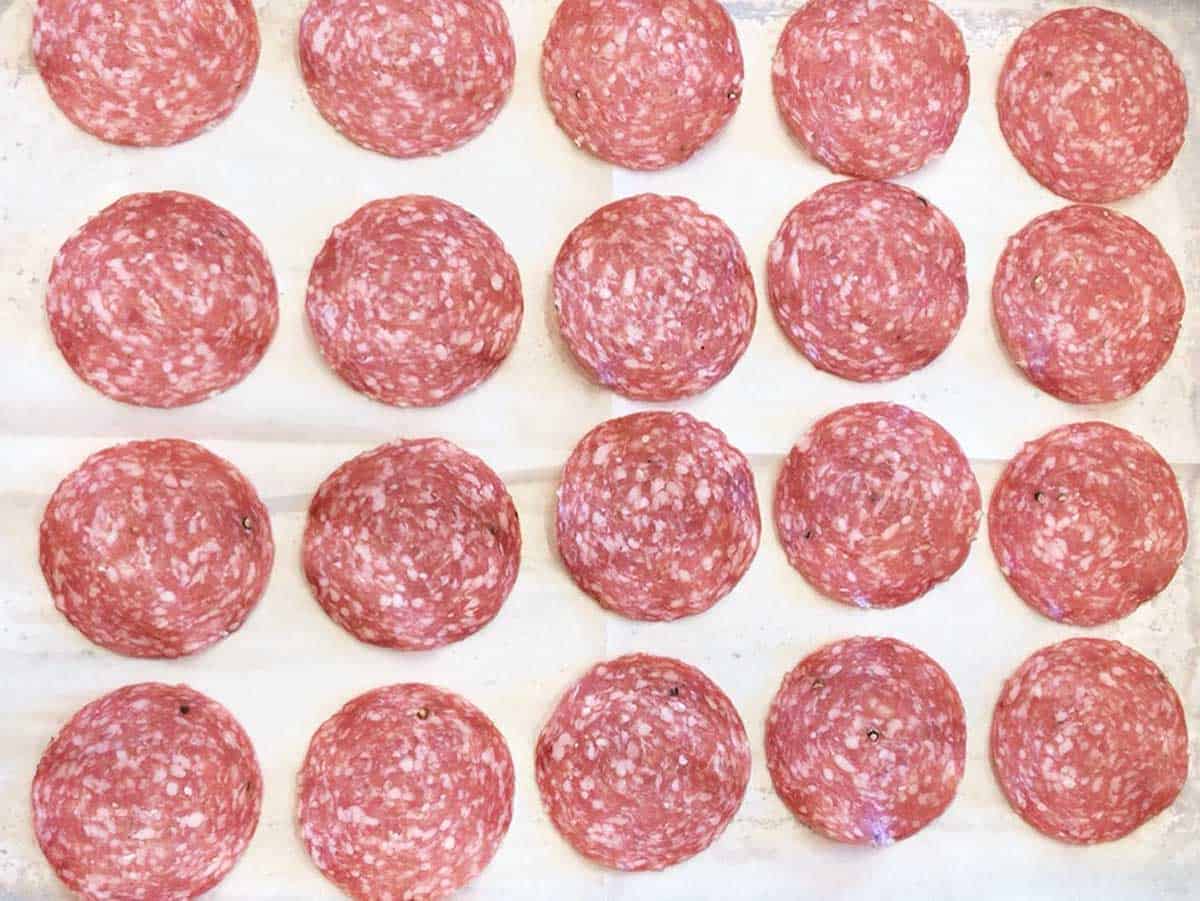The salami was arranged on a parchment-lined baking sheet.