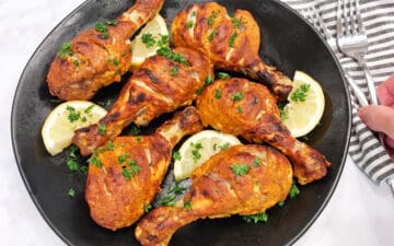 Tandoori chicken is served with lemon slices.