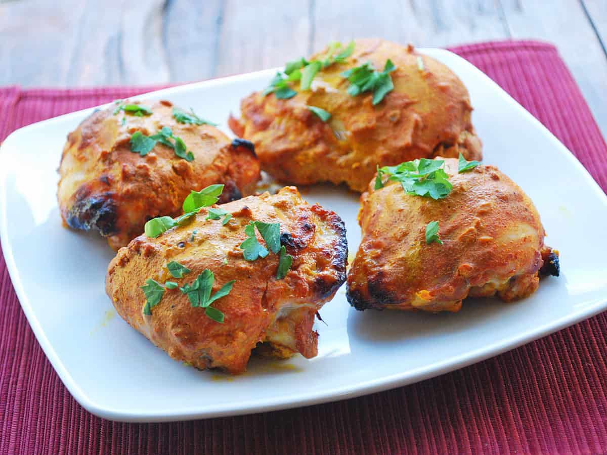 Tandoori chicken thighs on a plate.