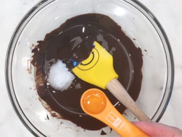 Adding coconut oil and sweetener to the melted chocolate.