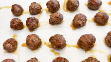 Baked meatballs on a baking sheet.