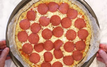 Returning the pizza to the oven after adding the toppings.