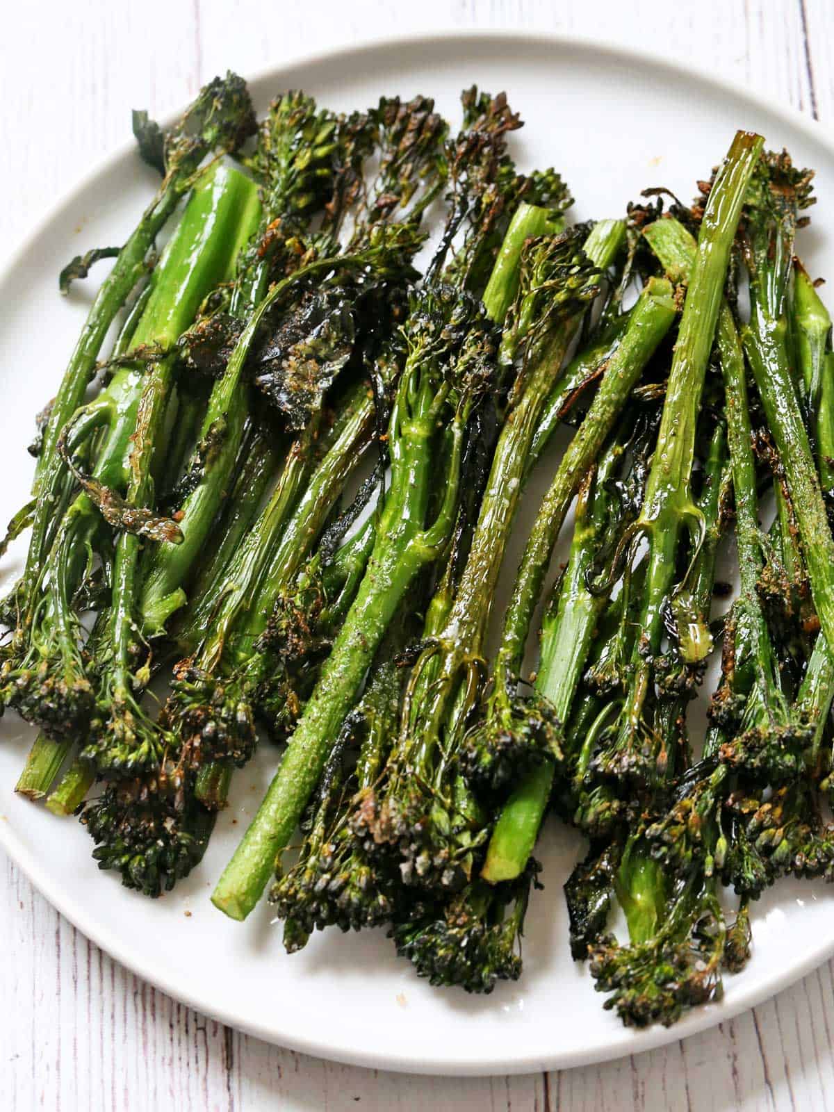 Roasted broccolini is served on a white plate.
