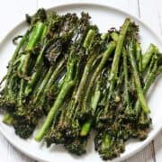 Roasted broccolini is served on a white plate.