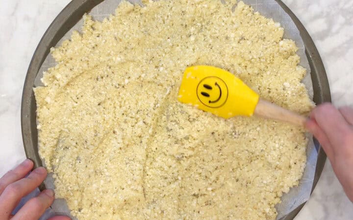 Spreading the mixture on the pizza pan.