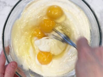 Adding eggs to the batter.