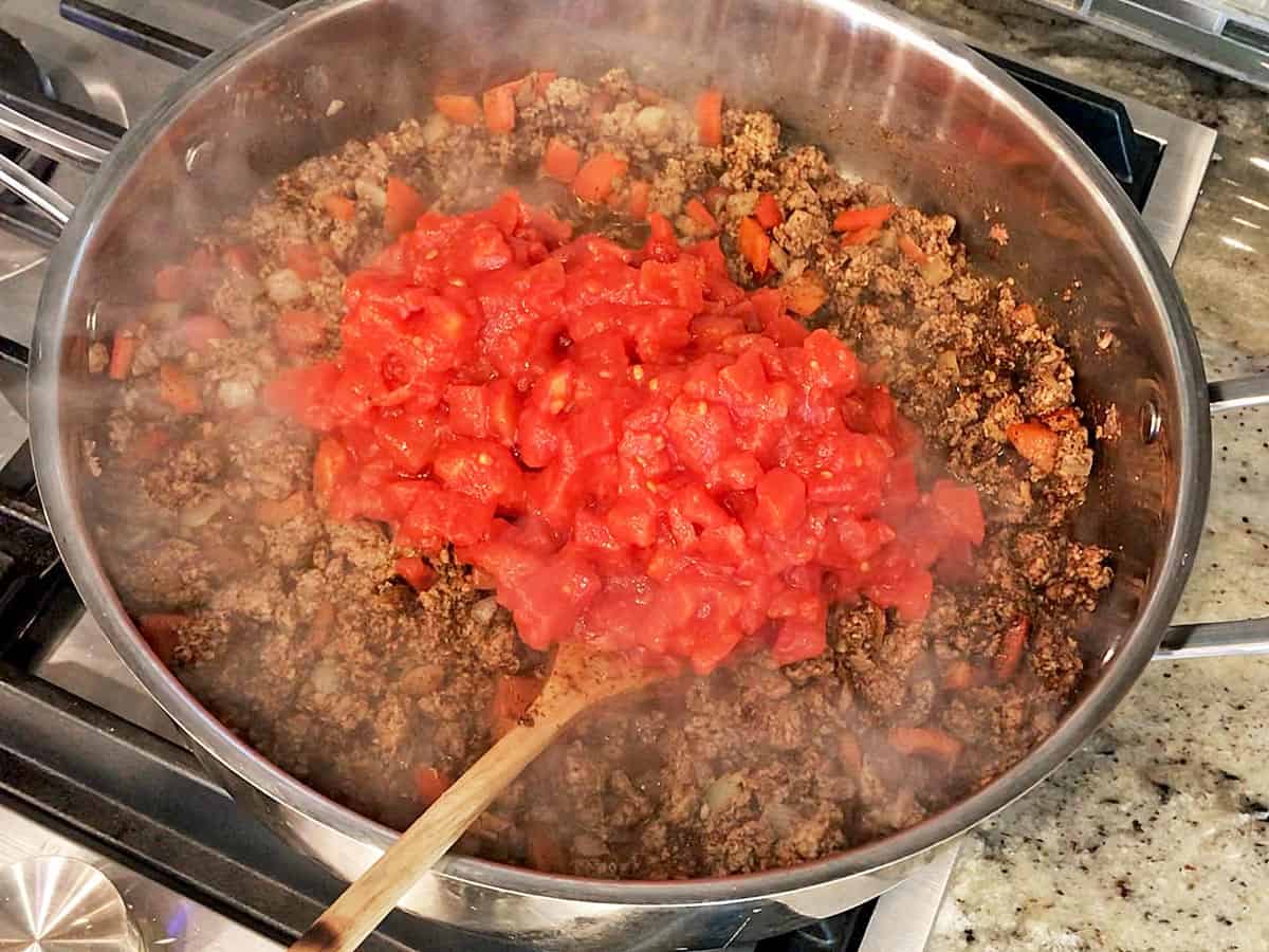 Adding tomatoes to the chili.