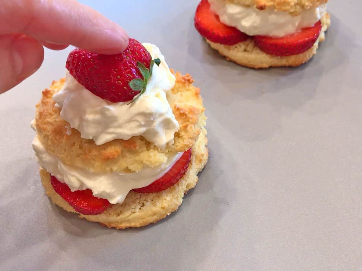 Topping an assembled cake with half a strawberry.