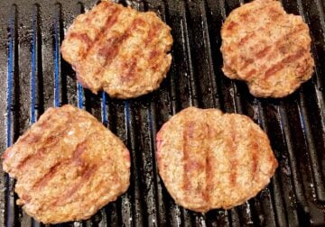 Four burgers on a grill.