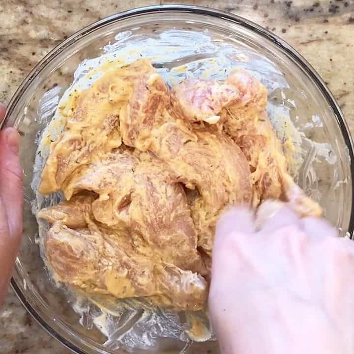 Coating the chicken pieces in the mayo-mustard mixture.